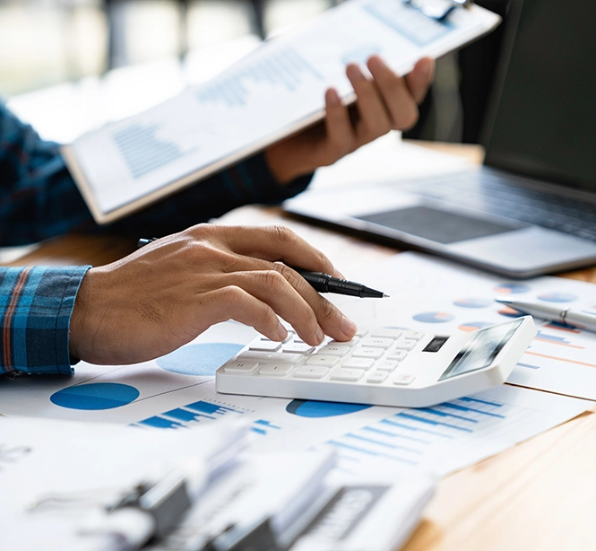 Finanzpersonal drückt auf einen Taschenrechner, um den Umsatz und den Gewinn des Unternehmens zu berechnen